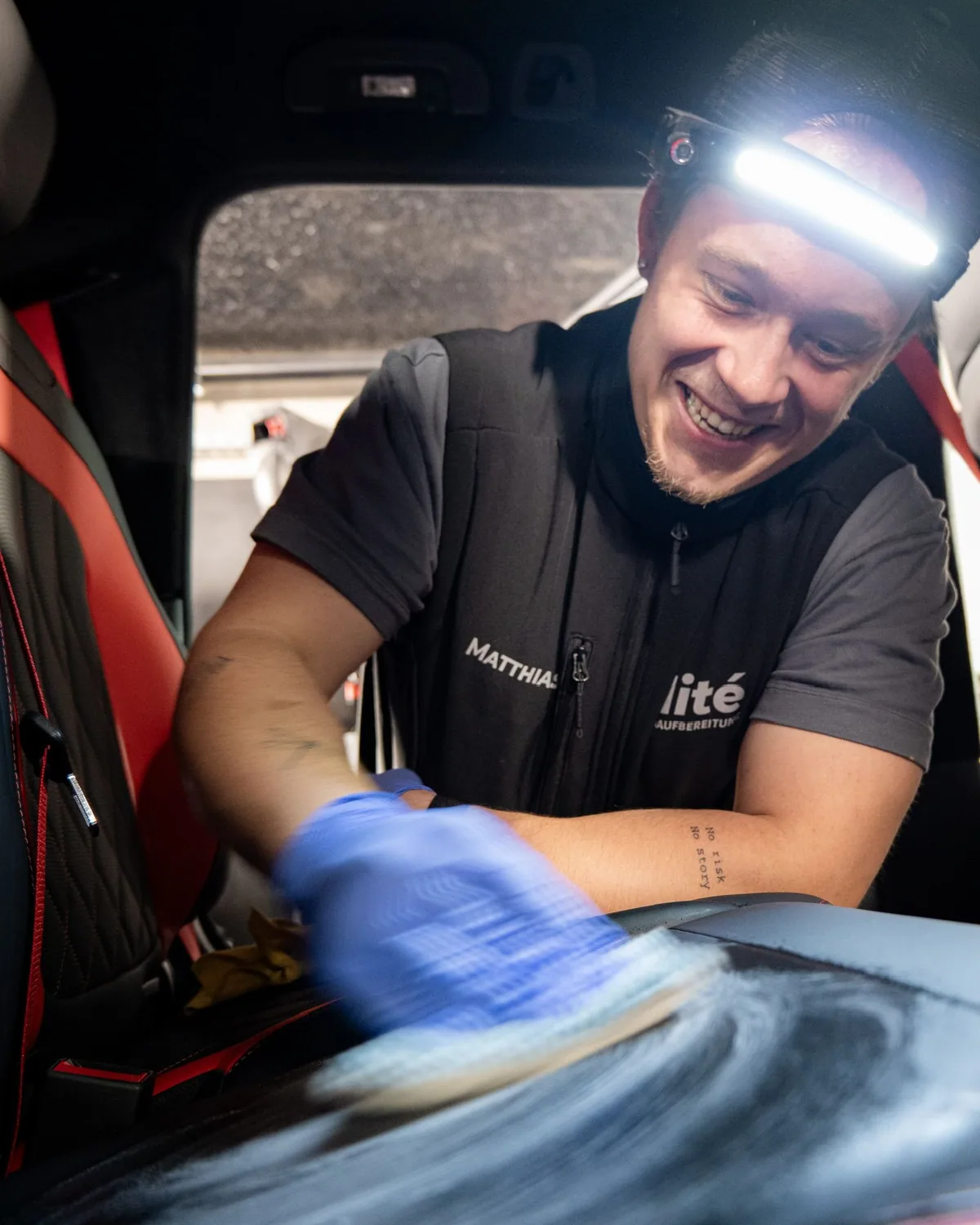 Elité-Mitarbeiter mit Stirnlampe reinigt das Armaturenbrett
